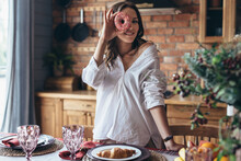 Young Woman Looking Through A Hole In A Doughnut At Home In The Kitchen