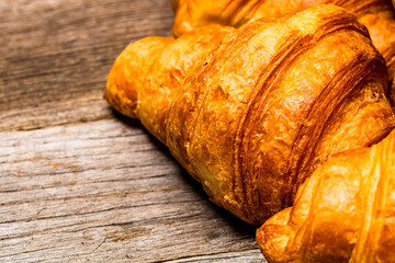 Wall Mural - Closeup shot of a delicious and fresh croissant isolated on a wooden board.