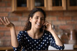 © fizkes - Happy pretty young latin woman holding distant smartphone call conversation, sharing good news with family or discussing ideas with friends, sitting at table in kitchen, distant communication concept.