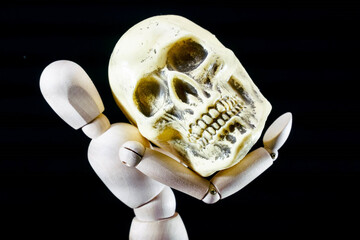 Sticker - Human wooden dummy holding a big skull, isolated on black