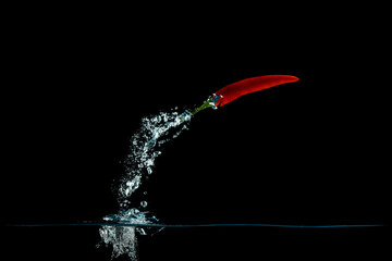 Sticker - Closeup shot of red pepper in the water on a black background