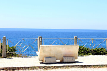 Sticker - Serene veiw of an empty bench facing the azure sea on a sunny day