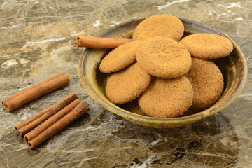 Wall Mural - Cinnamon spice cookies in brown ceramic bowl with cinnamon sticks