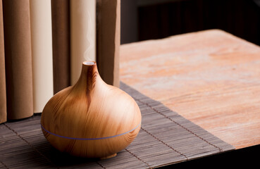 Essential oil air freshener on wood, with books on table, brown background.