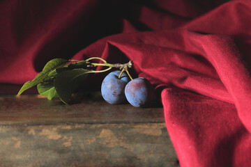 Sticker - Closeup o Plums with leaves on wooden table and red cloth