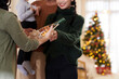© DragonImages - Hands of senior woman giving decorated bottle of champagne or wine to adult daughter as Christmas present