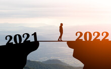 Silhouette Of  Person Walking From 2021 To 2022 Number On Top Of Mountain At Sunrise On 2022 Side And Space Background , Changing Year And  Better Future Concept