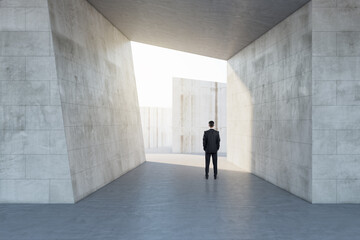 Poster - Businessman standing in abstract concrete tile space interior background with sunlght. Design and abstraction concept.