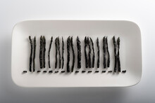 Tray With Black Asparagus Stalks Resembling Bar Code Symbolizing Genetically Modified Food
