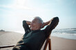 © Westend61 - Smiling senior man with hands behind head relaxing at beach
