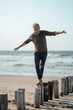 © Westend61 - Carefree senior man balancing on wooden posts at beach