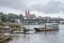 Switzerland, Basel-Stadt, Basel, Small Ferry Waiting On River Rhine Canal With Bridge And Basel Minsterin Background
