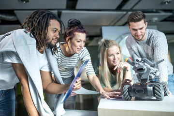 Technician with colleagues looking at combat car in robotic workshop