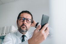 Dissatisfied And Not Pleased Businessman Taking Selfie With Smartphone In Office