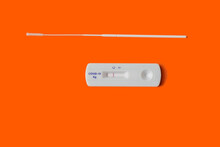 Rapid Covid 19 Antigen Test, Small Plastic Tester On Orange Background Showing Negative Result. Testing Swab Next To It.