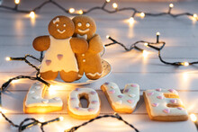 Gingerbread Couple Boy And Girl With Big Letters Love On The Background Of Garlands.