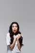 © LIGHTFIELD STUDIOS - young shocked woman with long wavy hair and clenched hands isolated on grey