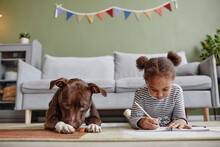 Front View Portrait Of Cute African-American Girl Lying On Floor With Big Dog, Copy Space