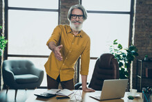 Photo Of Friendly Senior Man Wear Yellow Shirt Glasses Giving You Arm For Handshake Indoors Workplace Workstation