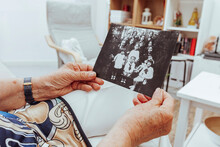 Portrait Of Mature Woman Hands Looking At Old Picture Of Her Family Made Many Years Ago. Grandmother Remembering Memories Of Family Members With Nostalgia And Melancholy At Home.