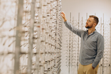 Canvas Print - Young man choosing spectacles at optic shop