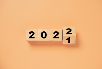 Wall Mural - Wooden cube block flipping from 2021 to 2022 on orange background , preparation for merry Christmas and happy new year.