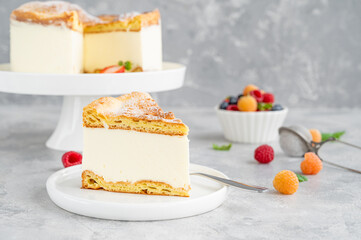 Traditional Polish cake Karpatka on a gray concrete background. Cake of choux pastry dough and custard cream with fresh berries and powdered sugar on top. Carpathian cake. Copy space.