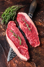 Uncooked Raw Top Sirloin Cap Or Rump Beef Meat Steaks On A Butcher Knife. Dark Background. Top View