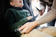© Seventyfour - Close up of man buckling son in back seat of family car, copy space