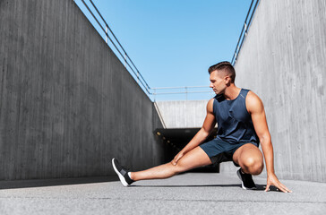 fitness, sport and healthy lifestyle concept - man exercising and stretching leg outdoors