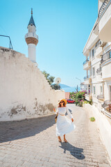 Sticker - Woman tourist walks through the picturesque streets of the coastal and resort town of Kas with mosque minaret