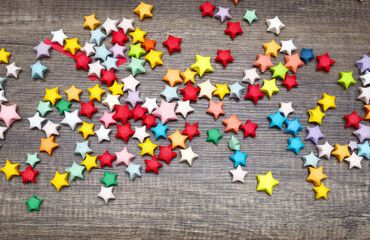 Wall Mural - Colorful paper lucky stars on wooden table