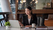 © amnaj - Portrait of smiling beautiful Asian businesswoman enjoy the idea on laptop computer sitting at office.