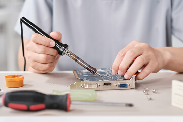 Poster - Hands of young contemporary technician with soldering iron repairing motherboard with microchip