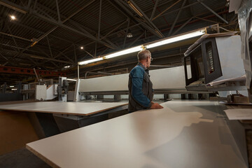 Concentrated grey-haired man working on the factory