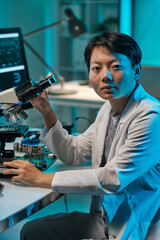 Poster - Young Chinese woman in whitecoat looking at camera while working with microscope in technical laboratory