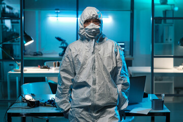 Poster - Young contemporary technician or scientist in protective workwear standing against desk with laptop and hardware