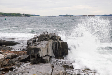 Waves crashing on rocks and creating upward mist spray. Portland, Maine.
