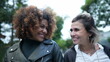 © Marco - Two happy women diverse friends walk together in urban street