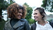 © Marco - Two happy women diverse friends walk together in urban street