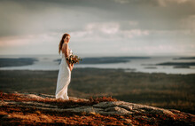 Bride White Dress Stands On Rocky Mountain At Sunset On Maine Coast