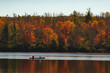 © Cavan Images - People kayaking in lake by autumn forest