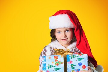 Sticker - Portrait of a satisfied little child in Christmas Santa hat. Holds a gift box. Preparing for the New Year holidays