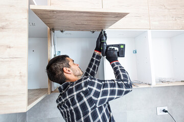 Wall Mural - The carpenter sets the door of the kitchen shelves