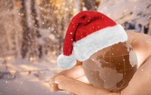 Merry Christmas. Kid Holding Earth Globe With A Santa Hat With Snowflakes