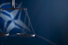 Conceptual Image Of Scales Of Justice On Flag Of NATO Background As Symbol Of Justice, Collective Defence.