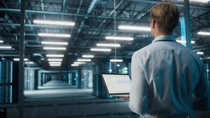Fototapete - Big Data Center Specialist Engineer Using Laptop Computer. Server Farm Cloud Computing Facility with System Administrator Working. Software as Solution and Cloud Computing with Cyber Security