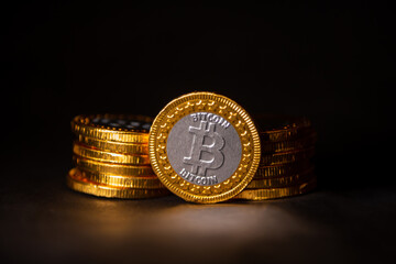 Poster - Close up of a golden bitcoin leaning on a pile of coins on a black background, Stock Market Concept