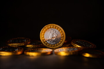 Poster - Closeup of a Bitcoin gold coin on a heap of Bitcoin coins with a black background