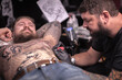 © Mr. Prof - Tattoo specialist making a tattoo in studio